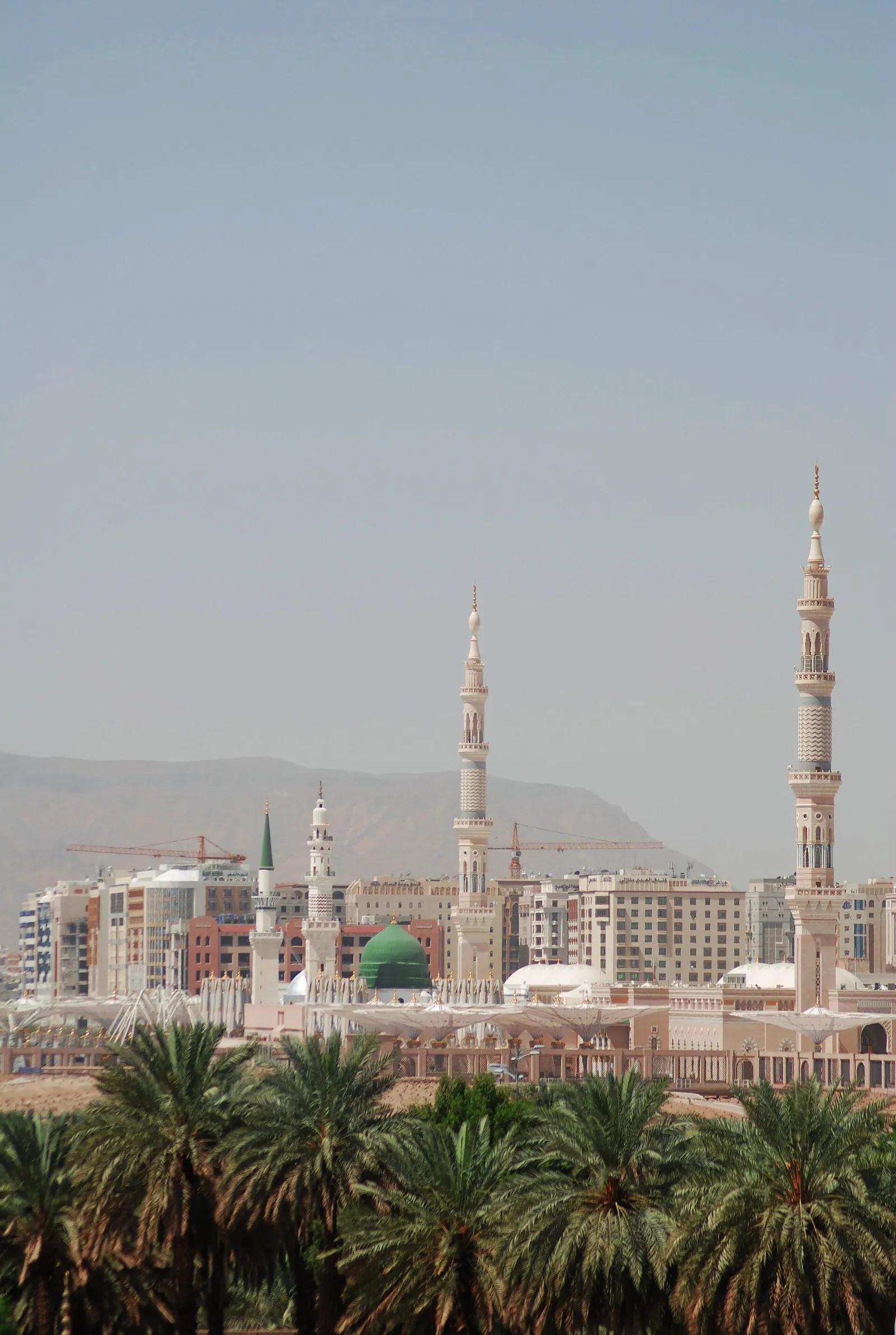 Medine'de hurma ağaçlarının ardında Mescid-i Nebevî'nin minareleri ve Yeşil Kubbe